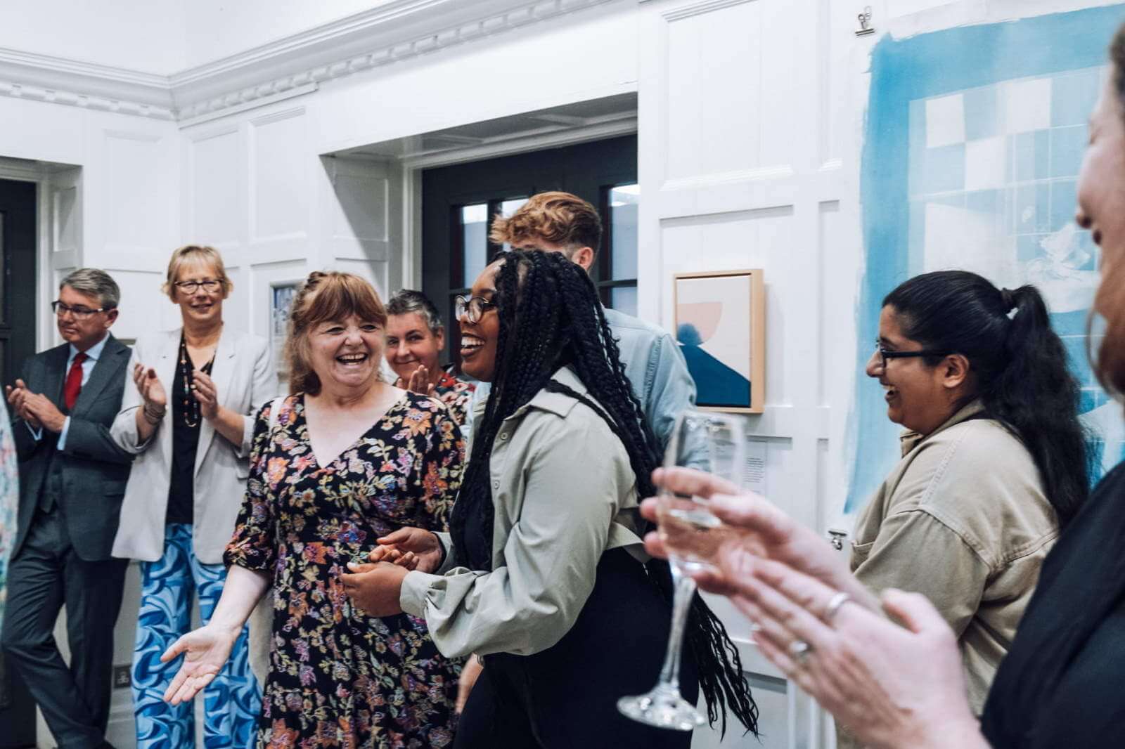 Image of an artist receiving an award and people surrounding her clapping