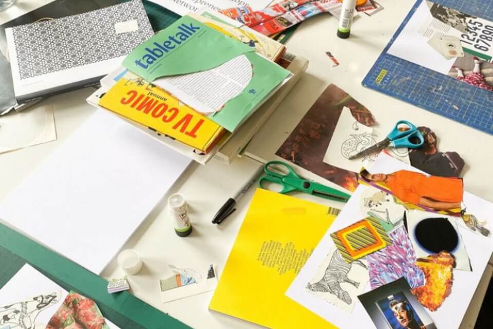 table full of colourful magazine and paper cuttings, glue, paper, scissors