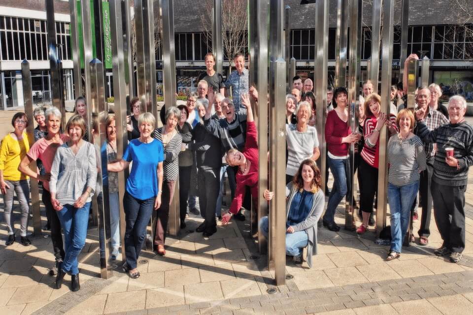 Group of men and women gathered amongst Keele University's 'Forest of Light' Sculpture