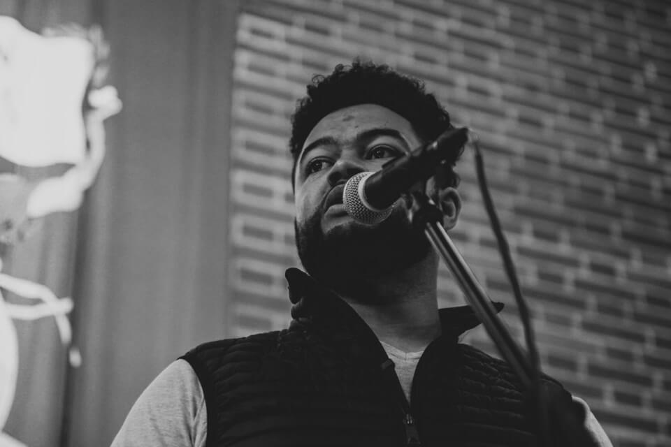 monotone photographic portrait of Casey Bailey speaking into a microphone.