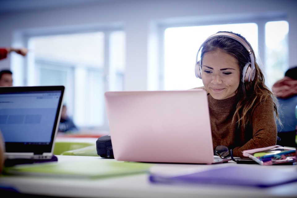 image of student wearing headphones and using a laptop