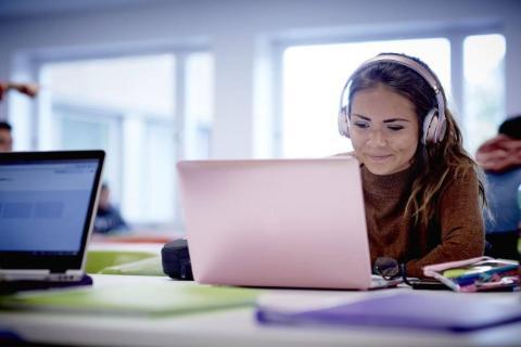 A student on a laptop with headphones in.