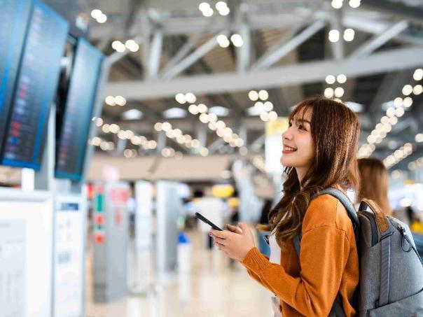 A student looking at a timetable at an airport.